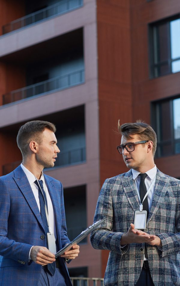 Group of business colleagues discussing business project together during meeting in the city with modern building in the background